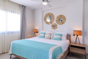 Un dormitorio con cama, dos espejos en la pared y lámparas de noche.