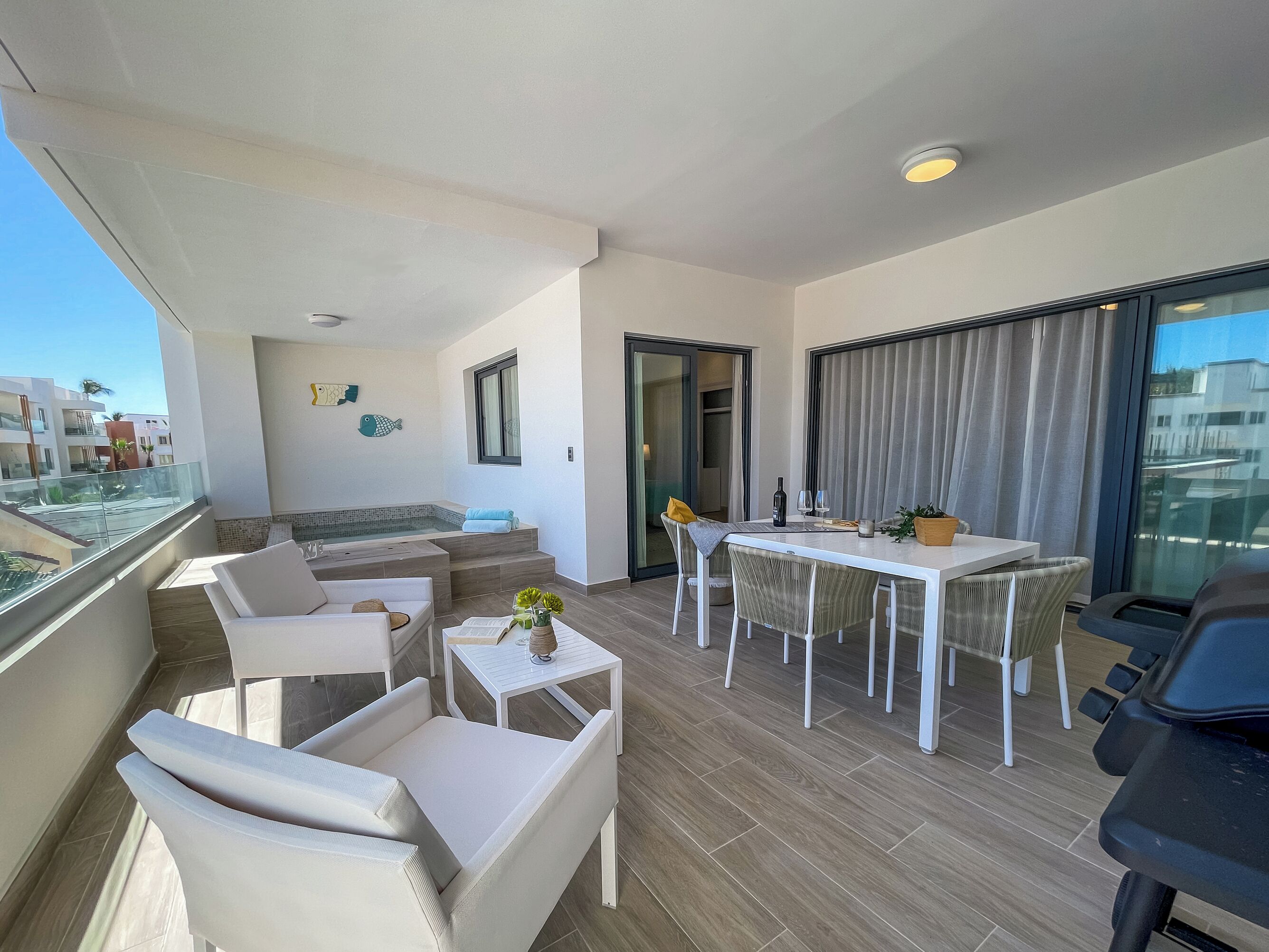 A balcony with a seating area, a dining table, and a grill.