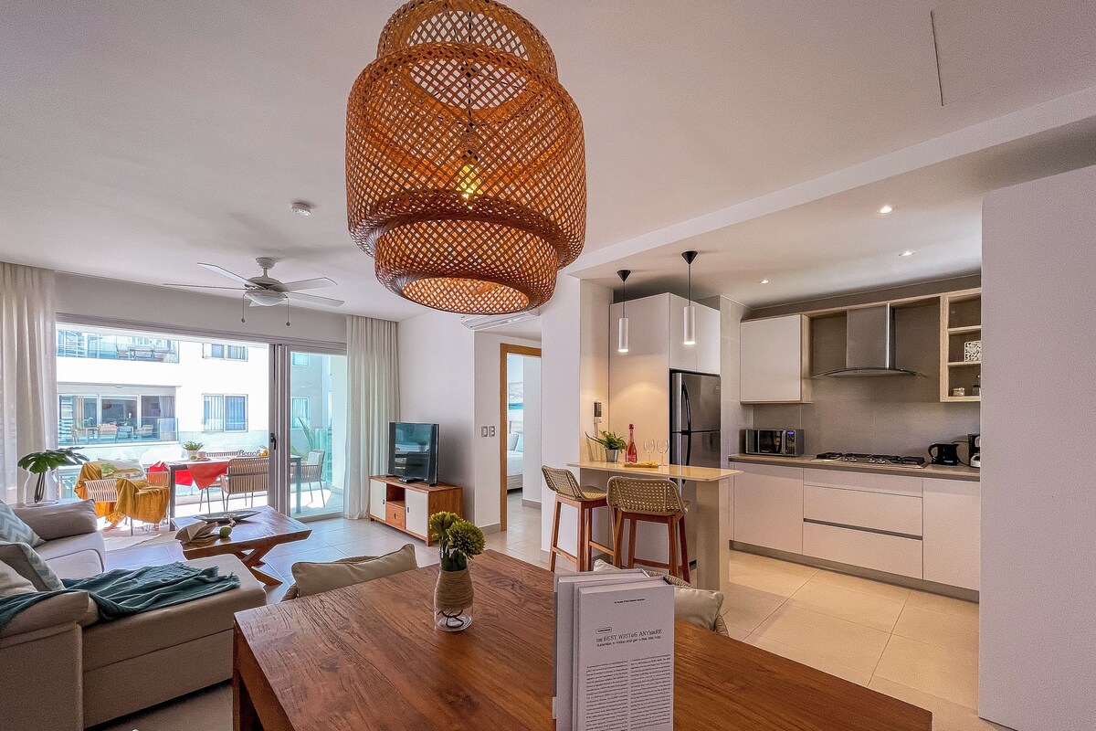 A modern living space with a dining area, kitchen, and a balcony with outdoor furniture.