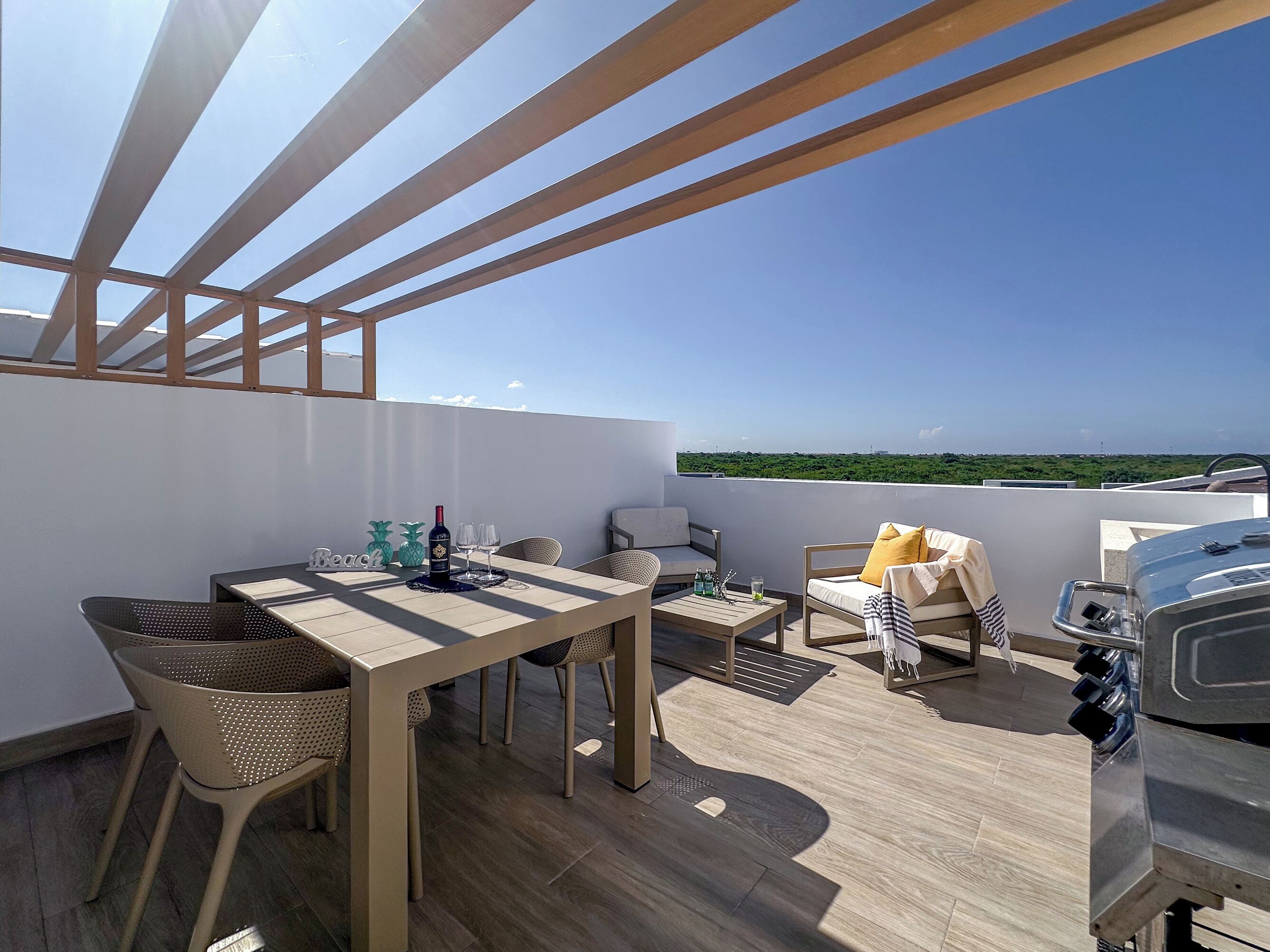 Una terraza en la azotea con una mesa, sillas, una parrilla y vistas al paisaje.
