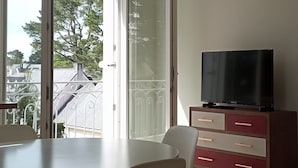 A modern living room with a dining area, a TV, and a large window with a view of the outside.