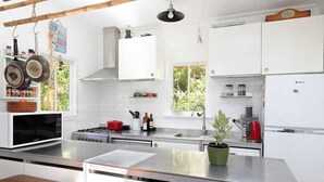 Una cocina moderna con armarios blancos, una isla de acero inoxidable y un colgador para ollas.