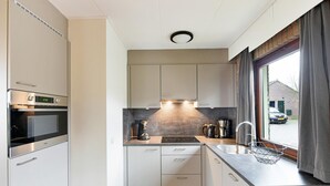 A modern kitchen with a built-in oven, microwave, and coffee maker. - South Limburg Stay Near Tripoint (Vijlen)