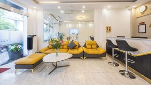 A modern hotel lobby with a yellow sofa, a round table, and a bar area. - A25 Hotel - 14 Ho Huan Nghiep (Ho Chi Minh City)