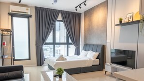 A modern hotel room with a large bed, a flat-screen TV, a desk, and a window with curtains. - HighparkSuites Petaling Jaya Kelana Jaya (Petaling Jaya)