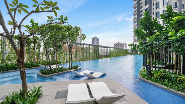 A modern outdoor swimming pool area with lounge chairs and greenery, surrounded by high-rise buildings. - HighparkSuites Petaling Jaya Kelana Jaya (Petaling Jaya)