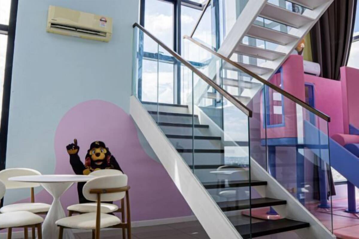 A modern interior with a staircase, a table with chairs, and a mascot character.