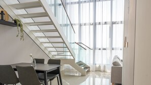 A modern interior with a dining area, staircase, and a sofa. - HighparkSuites Petaling Jaya Kelana Jaya (Petaling Jaya)
