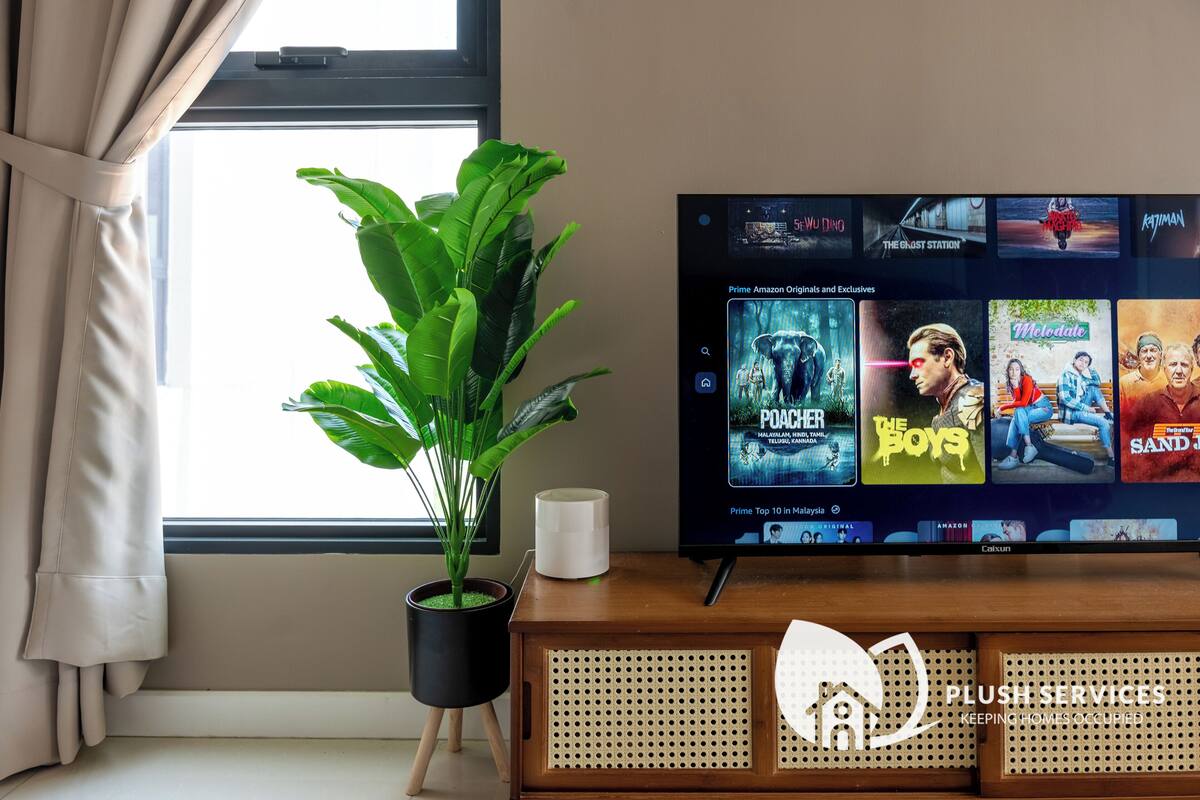 A television displaying a selection of movies and a potted plant beside it.