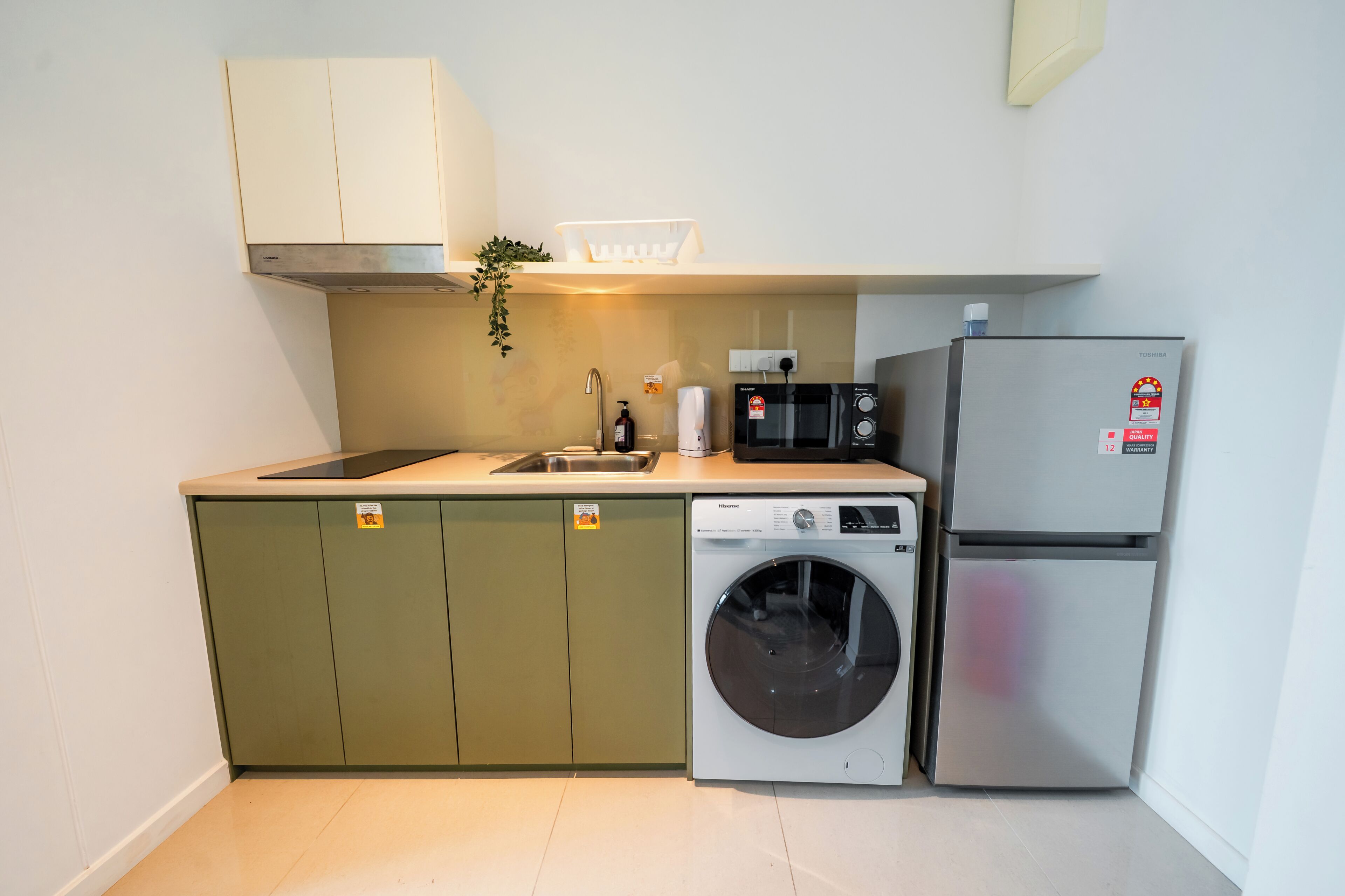 A compact kitchen with a washing machine, a microwave, and a refrigerator.
