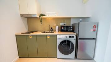 A compact kitchen with a washing machine, a microwave, and a refrigerator.