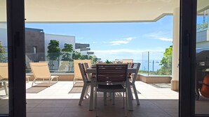 Un comedor con una mesa, sillas, una división de vidrio y vistas de la ciudad.