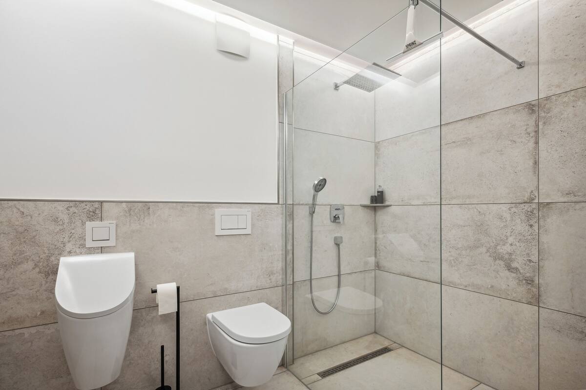 Un baño moderno con ducha de vidrio, inodoro blanco y bidé.