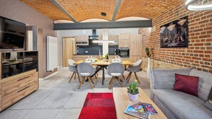 A modern kitchen with a brick ceiling, wooden cabinets, and a dining area with a red rug. - Apartmentferienhaus Schlag (Naumburg)
