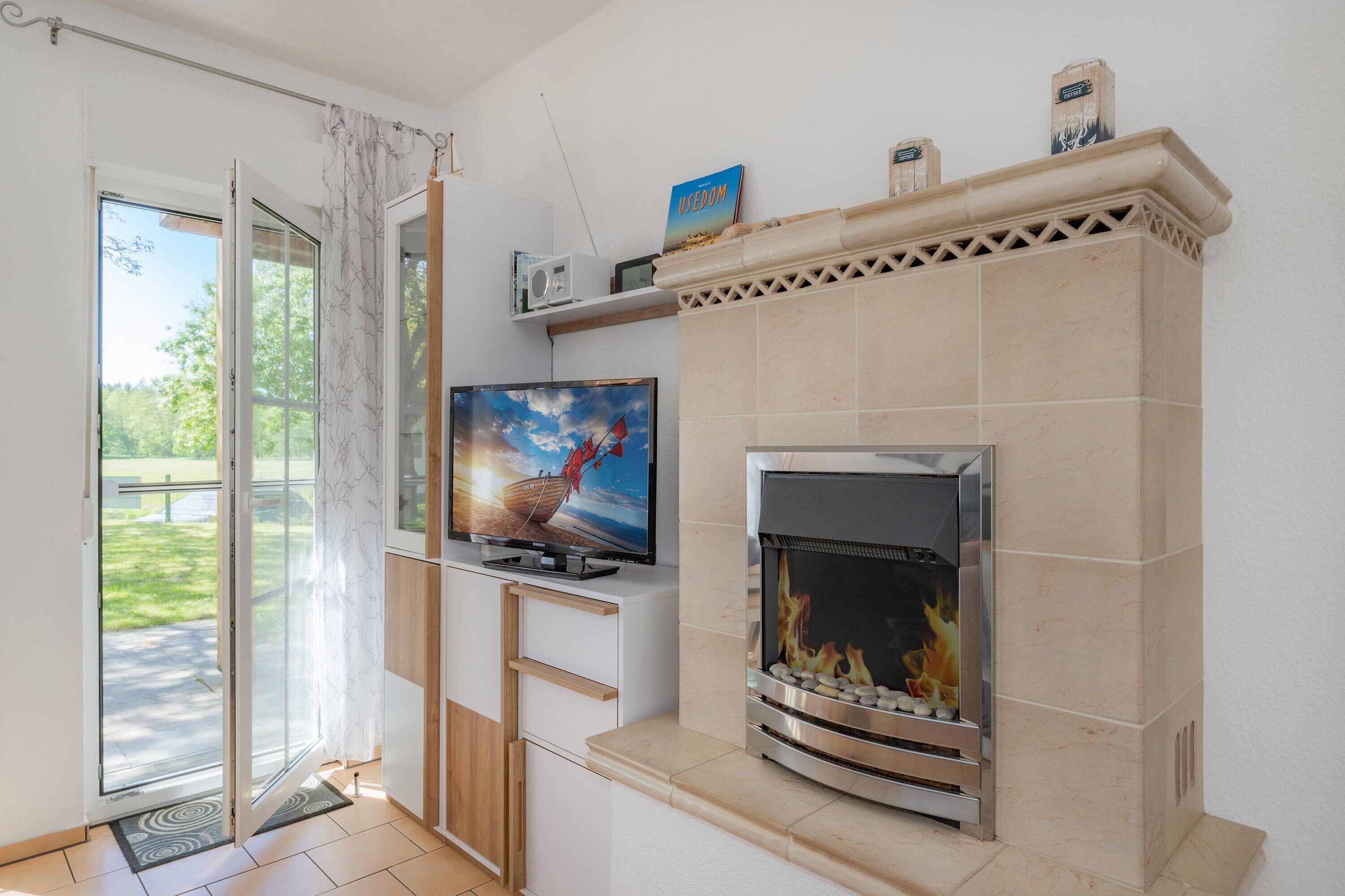 Ein modernes Wohnzimmer mit Fernseher, Kamin und Blick ins Freie.