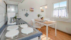 Une cuisine moderne dotée d’un plan de travail en granit, de quatre éviers blancs, d’une machine à café et d’un coin repas avec une table et des chaises.