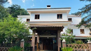 A two-story building with a tiled roof and a sign reading "Hotel de la Sierra." - Hotel El Refugio de Juanar (Ojén)
