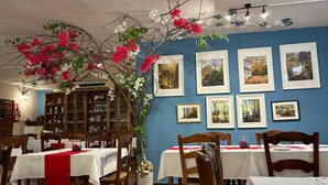 A restaurant with white tablecloths, wooden chairs, and a large floral centerpiece. - Hotel El Refugio de Juanar (Ojén)