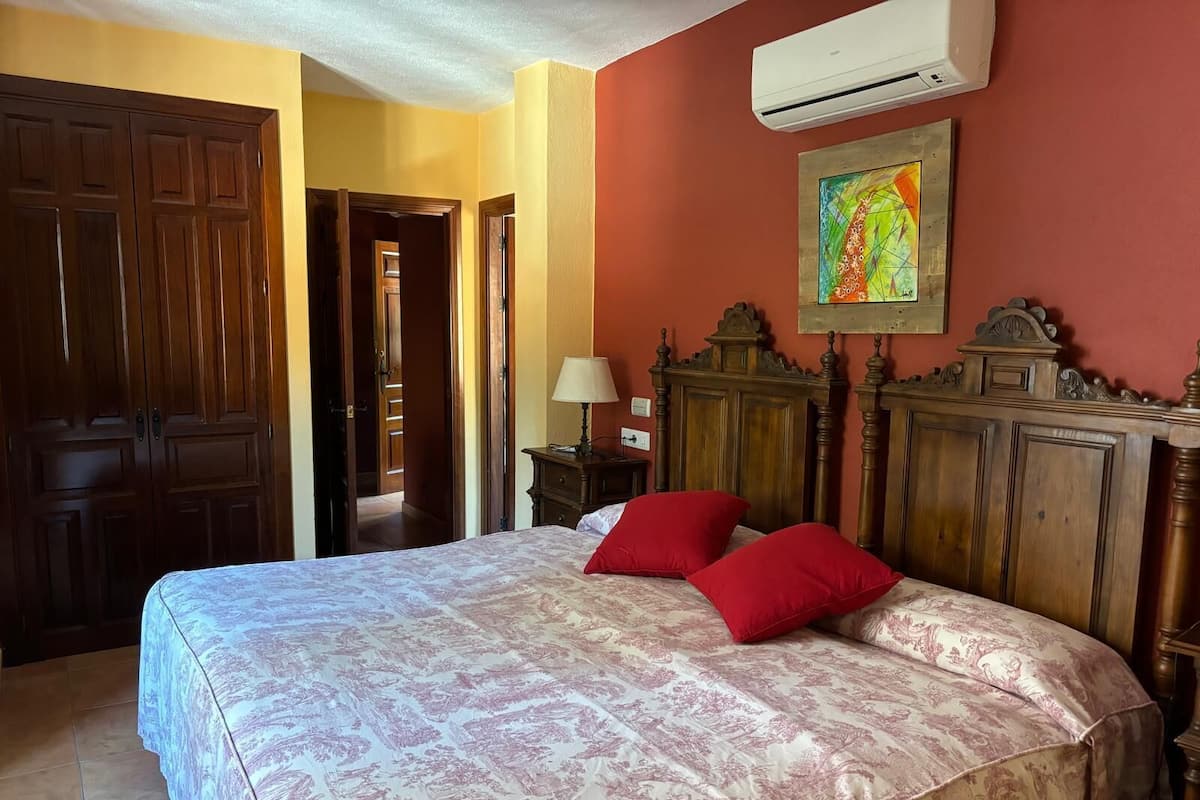 Ein Schlafzimmer mit einem großen Bett, einem Holzkopfende und einer roten Wand.
