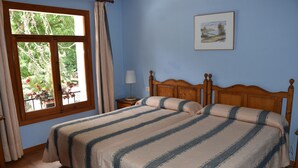 A bedroom with two beds, a window with curtains, a bedside table with a lamp, and a framed picture on the wall. - Hotel El Refugio de Juanar (Ojén)