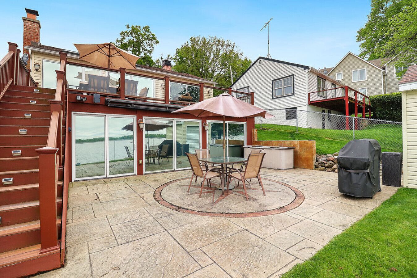 A patio with a table and chairs, a grill, and a covered barbecue grill.