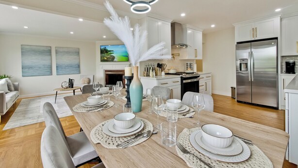 A modern kitchen with white cabinets, a stainless steel refrigerator, and a dining area set with white plates, bowls, and glassware. - 30% OFF / Easy Parking / Mins to SF / Lovely Backyard / Skyline View / Hottub (Daly City)