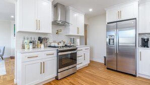 A modern kitchen with white cabinets, stainless steel appliances, and wooden flooring. - 30% OFF / Easy Parking / Mins to SF / Lovely Backyard / Skyline View / Hottub (Daly City)
