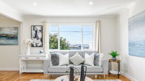 A modern living room with a grey sofa, a round coffee table, and artwork on the walls. - 30% OFF / Easy Parking / Mins to SF / Lovely Backyard / Skyline View / Hottub (Daly City)