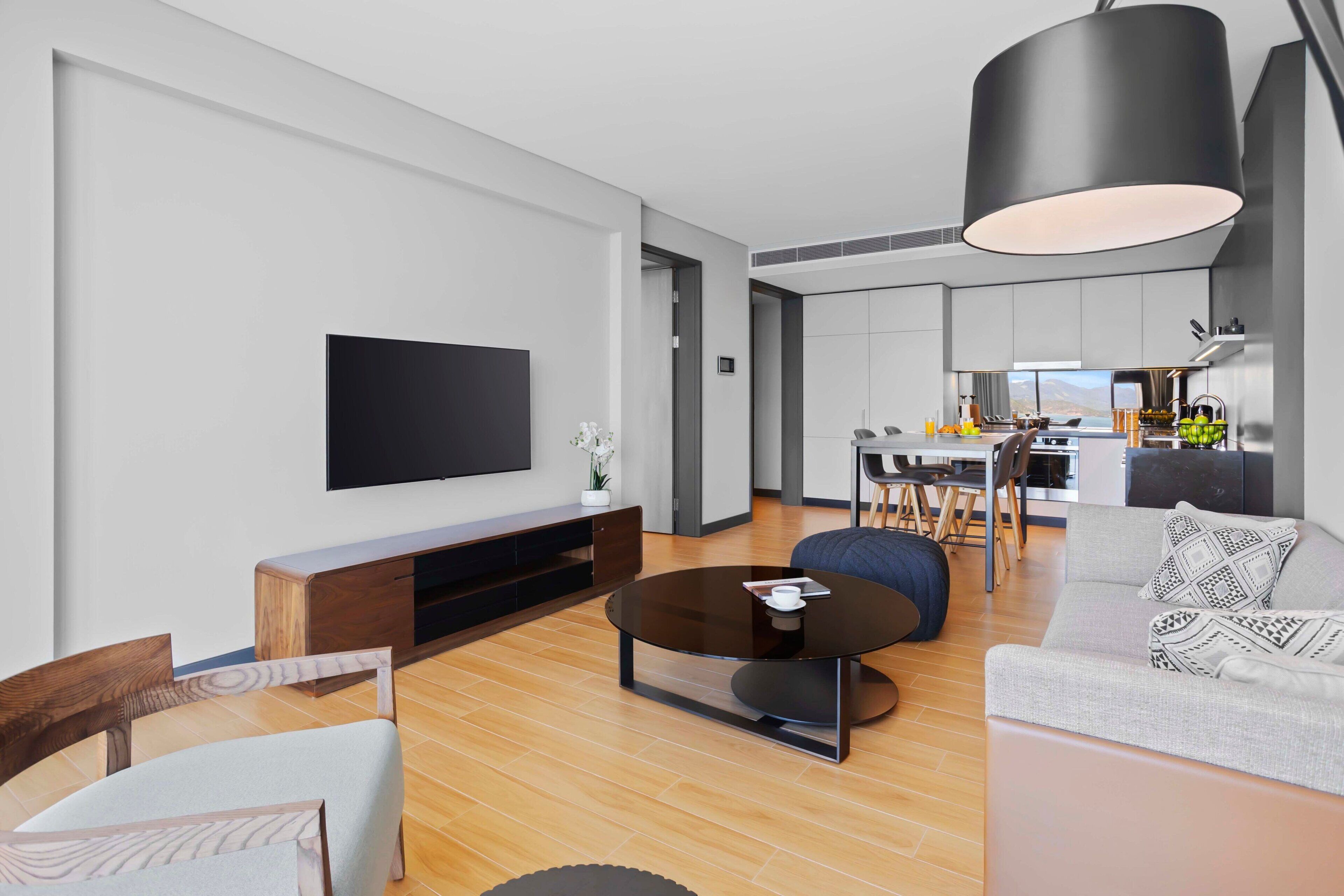 A modern living room with a flat-screen TV, a coffee table, and seating.