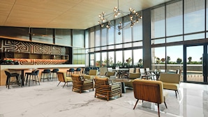 A spacious lobby with a bar area, seating arrangements, and large windows offering views. - Marriott Executive Apartments Port Moresby (Port Moresby)