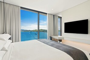 Habitación de hotel con una cama grande, un escritorio, un televisor de pantalla plana y vistas al mar.