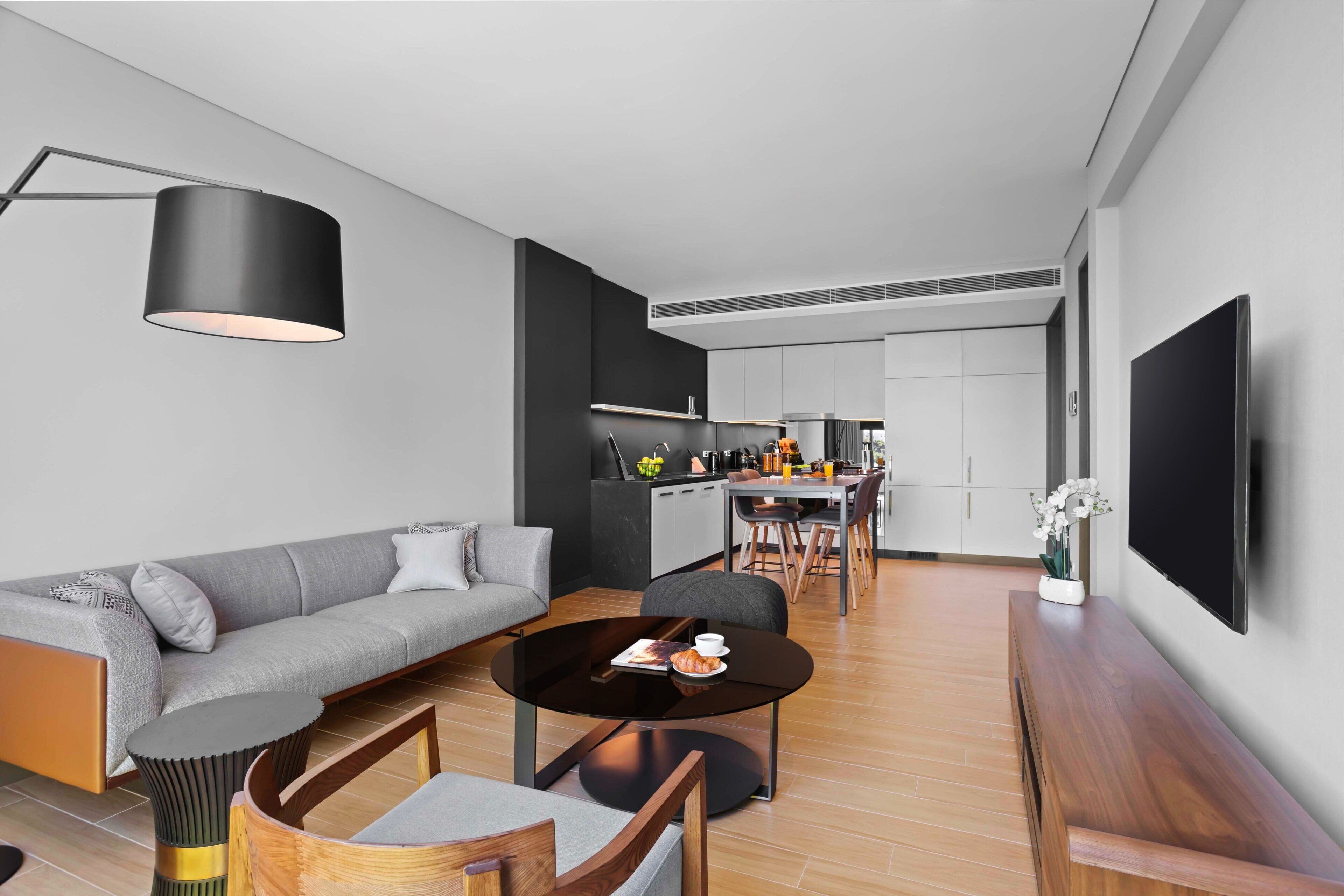 A modern living room with a grey sofa, a round coffee table, and a black floor lamp.