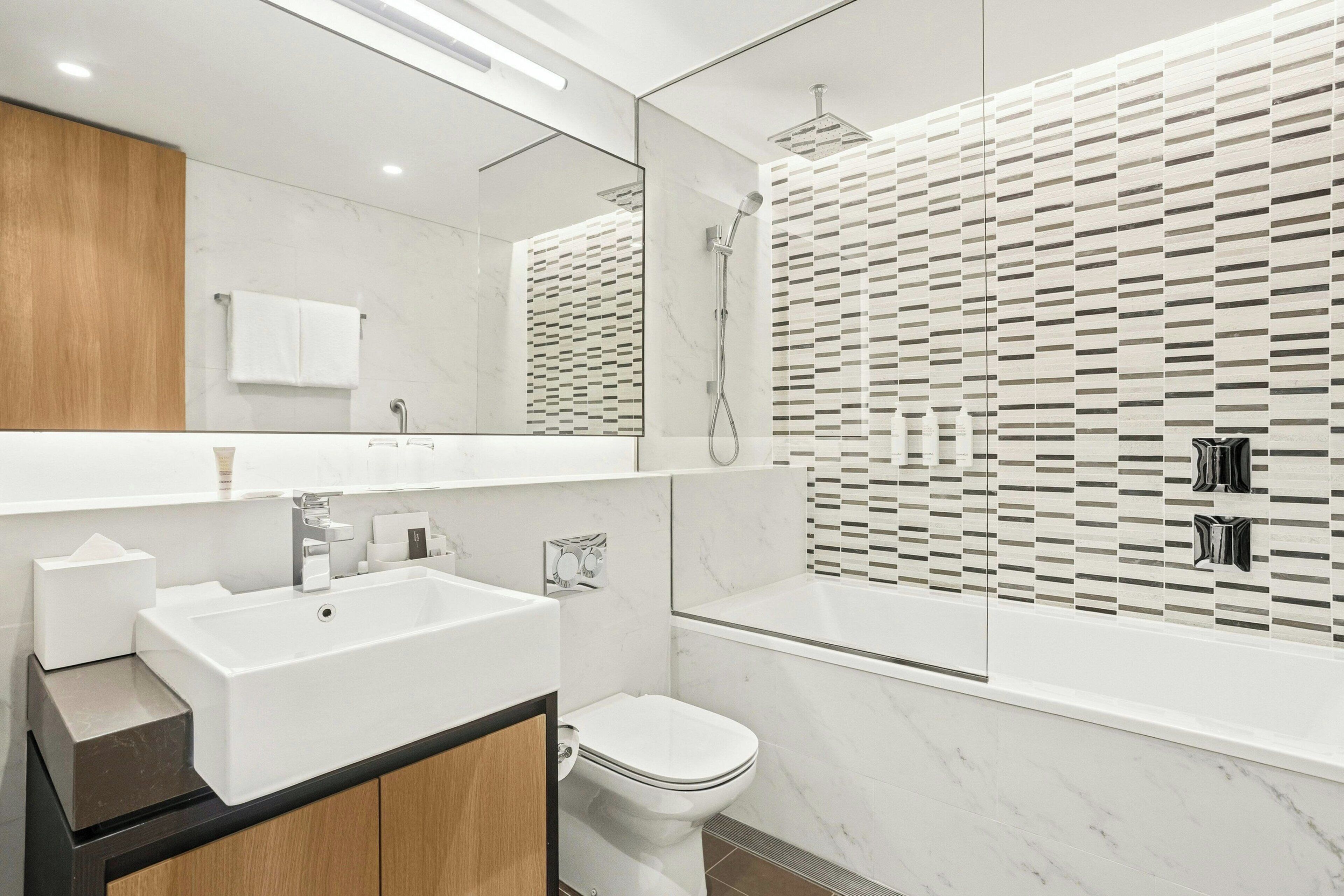 A modern bathroom with a white sink, mirror, and toilet.