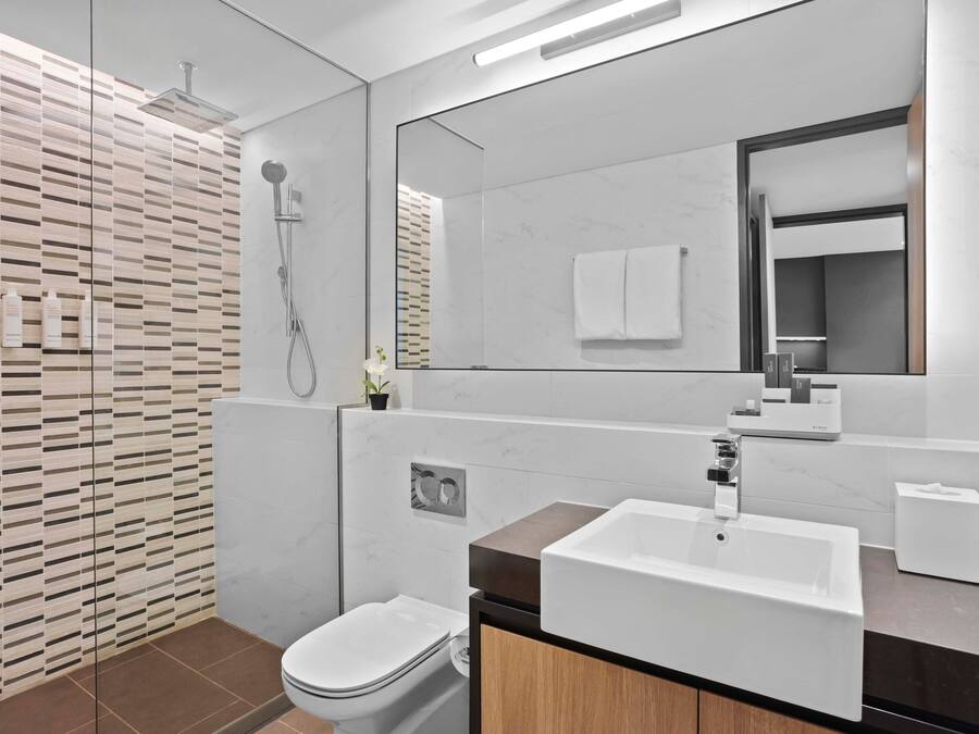 Een moderne badkamer met een grote spiegel, een witte wastafel en een douche.