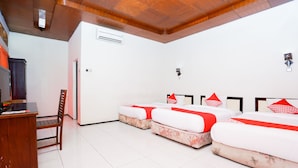 Een hotelkamer met drie bedden, een bureau en een airconditioning.