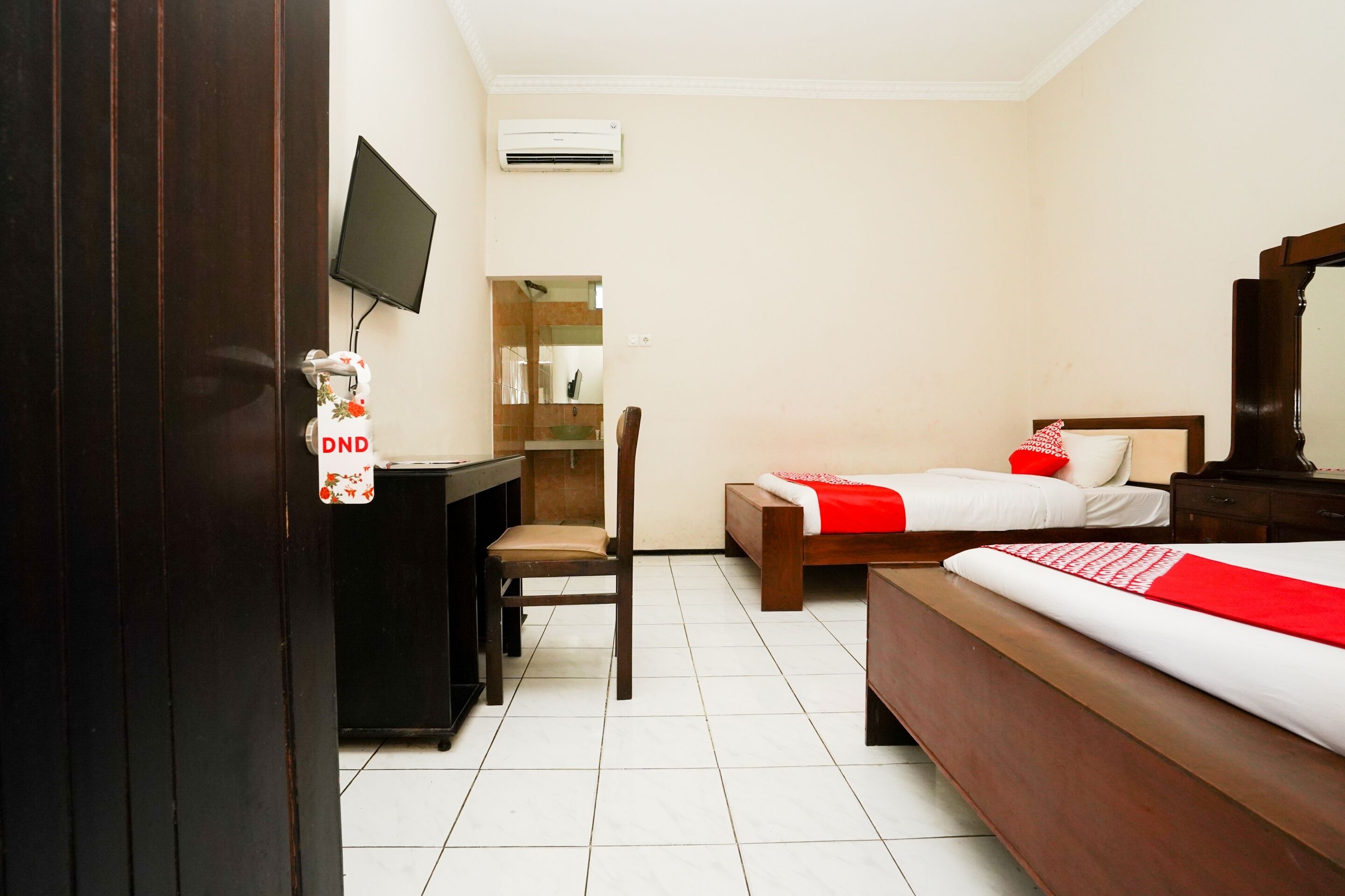 A hotel room with a bed, a desk, a chair, a TV, and a mirror.