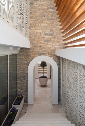 Stunning staircase leads to an upper level, flanked by walls with intricate patterns and a potted plant at its base.