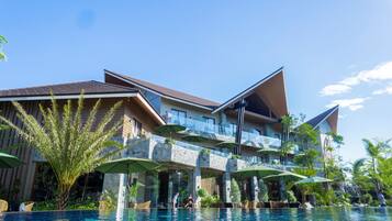 Relax by the infinity pool surrounded by lush greenery and outdoor seating areas.