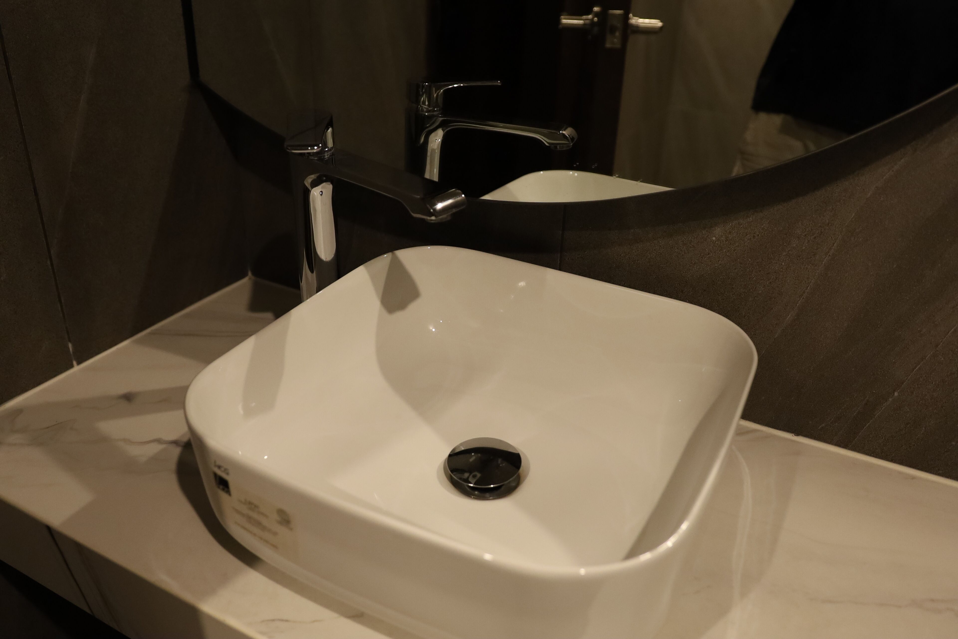 A white bathroom sink with a modern faucet and a mirror above it.
