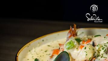 A bowl of seafood chowder with mussels and crab, served in a blue bowl.
