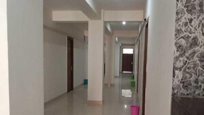 A spacious, well-lit corridor with a marble wall on one side and a plain wall on the other. - Hotel Soho Sector 51 Noida (Noida)