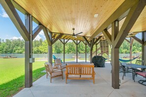 Eine überdachte Terrasse im Freien mit Holzbalkendecke, einer Hängematte, einem Tisch und Stühlen.