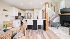 A modern kitchen with white cabinets, stainless steel appliances, and a central island with bar stools.