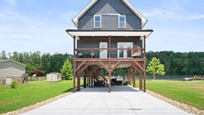 A two-story house with a covered deck and a staircase leading to an upper level.