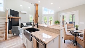 A modern kitchen with granite countertops, a built-in stove, and a dining area with wicker chairs and a glass table.