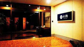 A reception area with a carpeted floor, a reception desk, and a sign with Japanese characters.