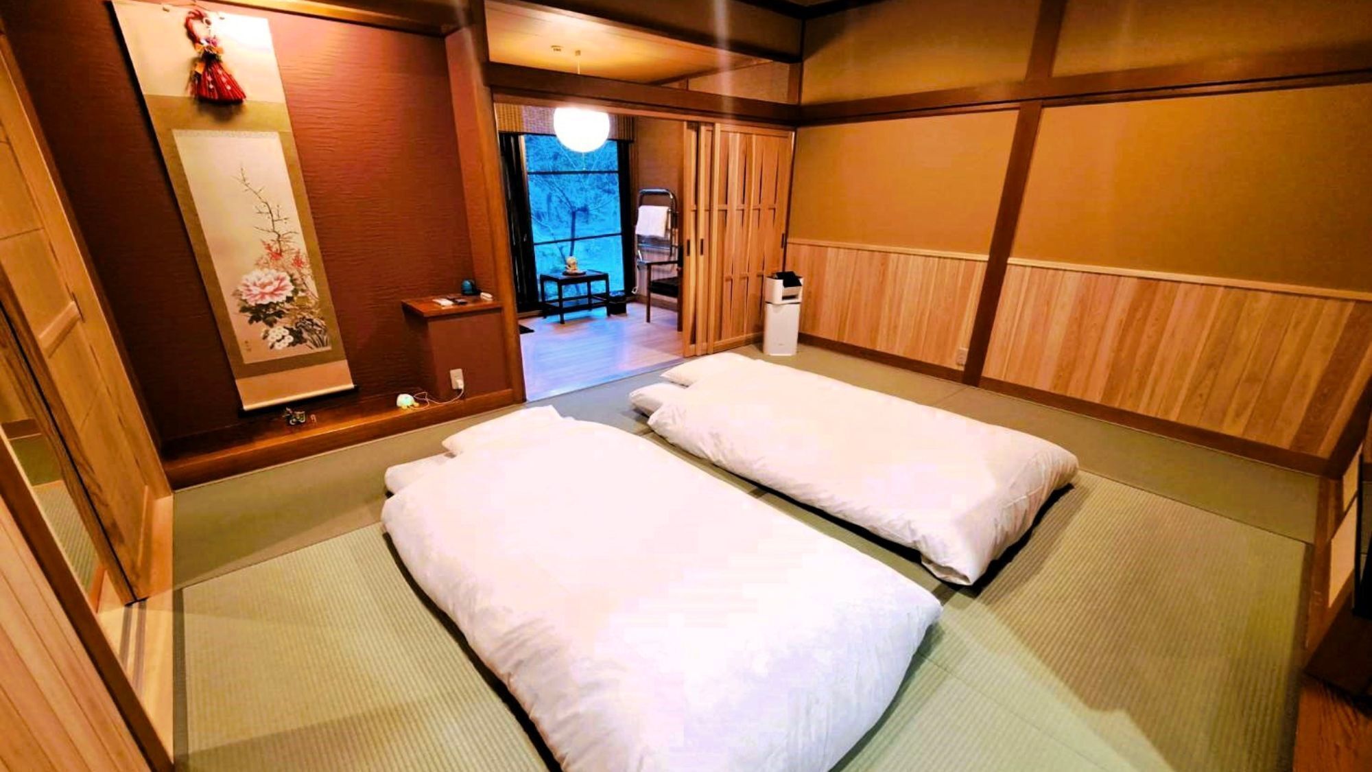 Una habitación japonesa tradicional con suelo de tatami, dos esteras de tatami, un celosía shoji y un pequeño armario de madera.