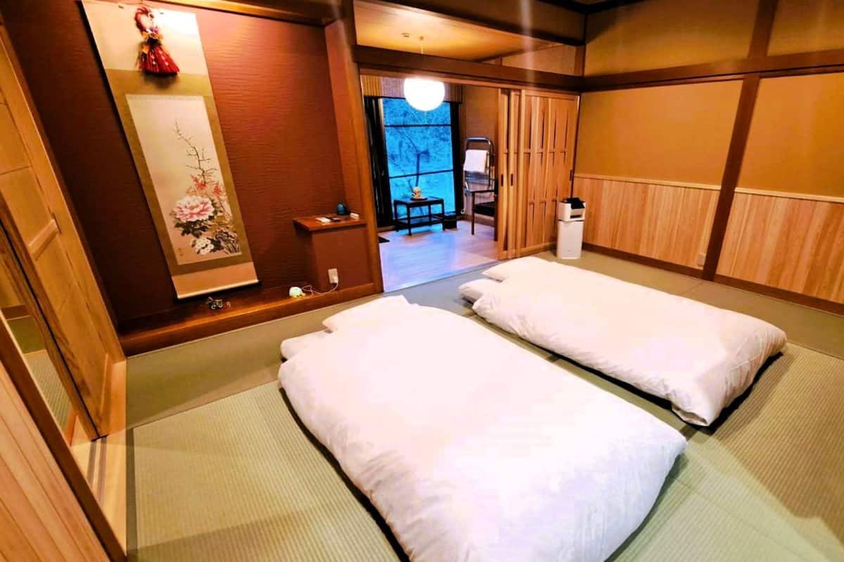 A traditional Japanese room with tatami flooring, two tatami mats, a shoji screen, and a small wooden cabinet.