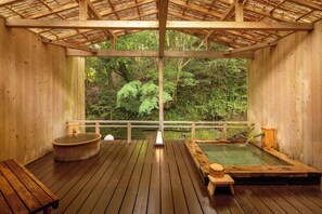 A wooden hot spring bath area with a wooden deck, benches, and a view of lush greenery. - MIZUMARI (Kawazu)