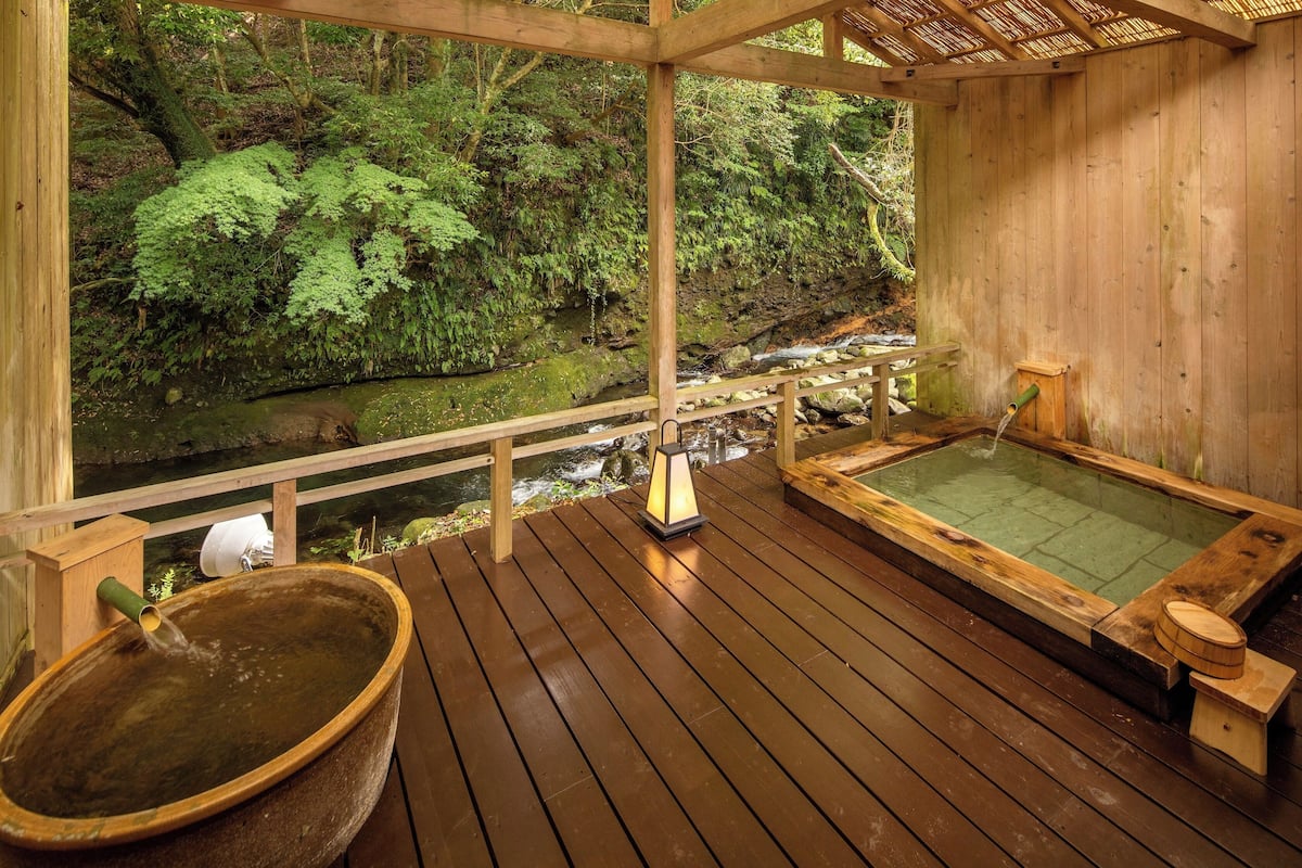 A wooden deck with a hot spring bath, a wooden bucket, and a lantern.